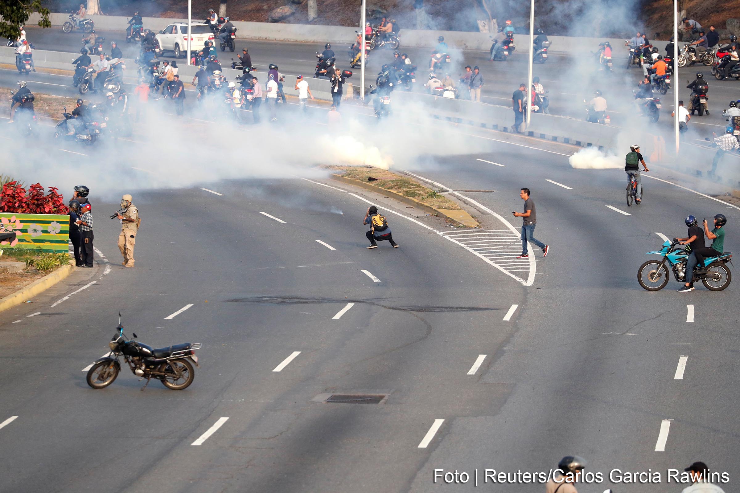 Partidários da oposição venezuelana reagem ao gás lacrimogêneo perto da Base Aérea "La Carlota", em Caracas, Venezuela.