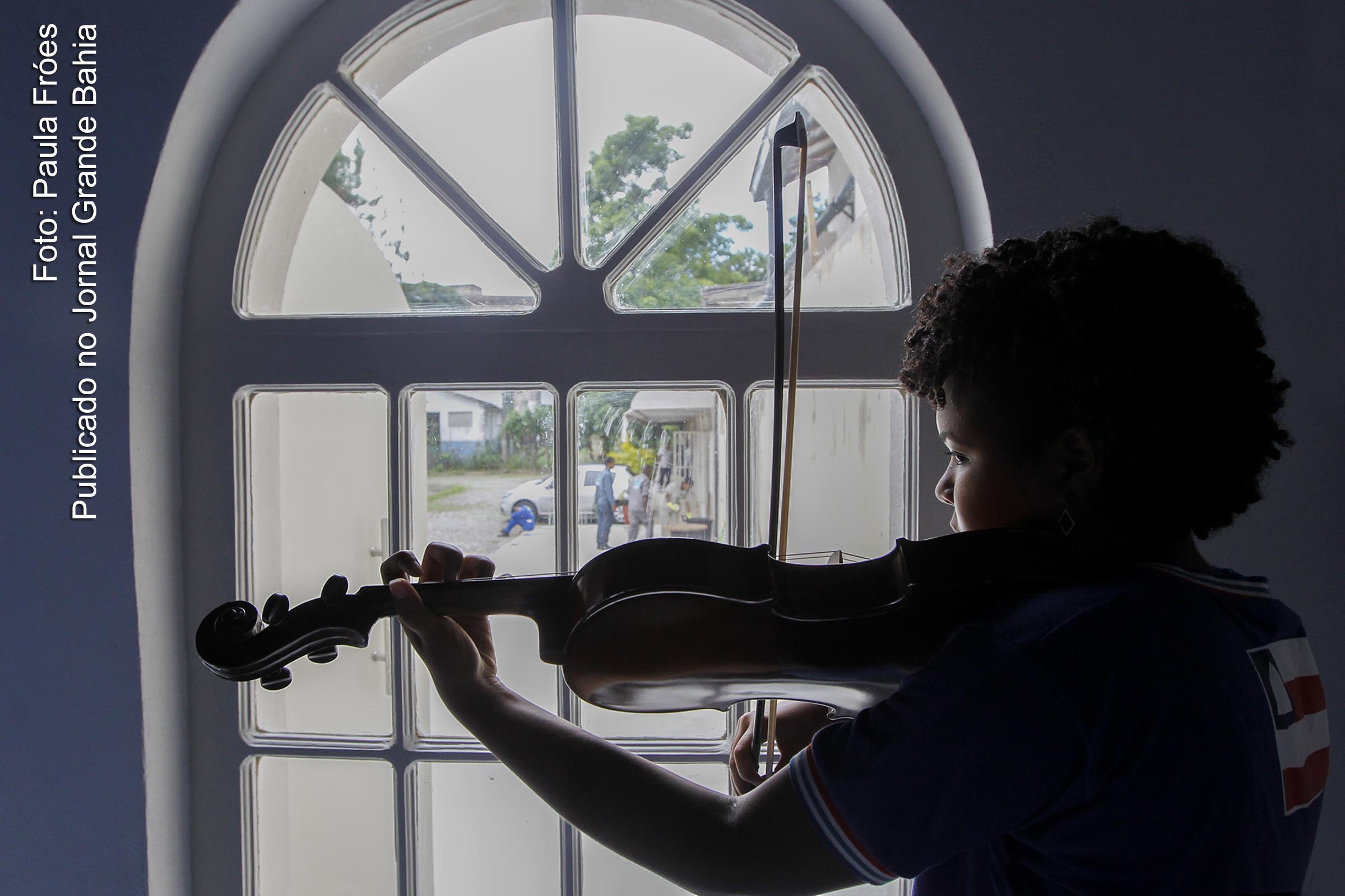 Aluna do projeto NEOJIBA toca violino. 